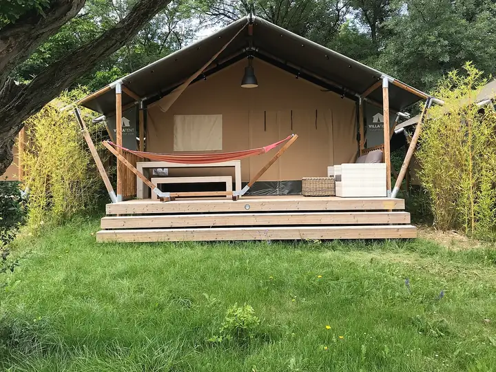Lodge en toile sur plancher en bois, avec terrasse et hamac